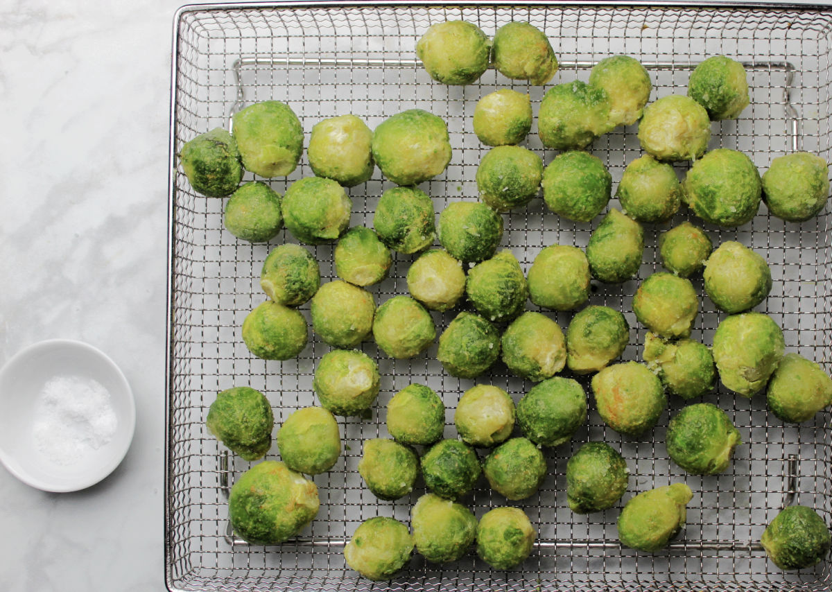 frozen seasoned Brussels Sprouts on an air fryer tray ready for the oven. 