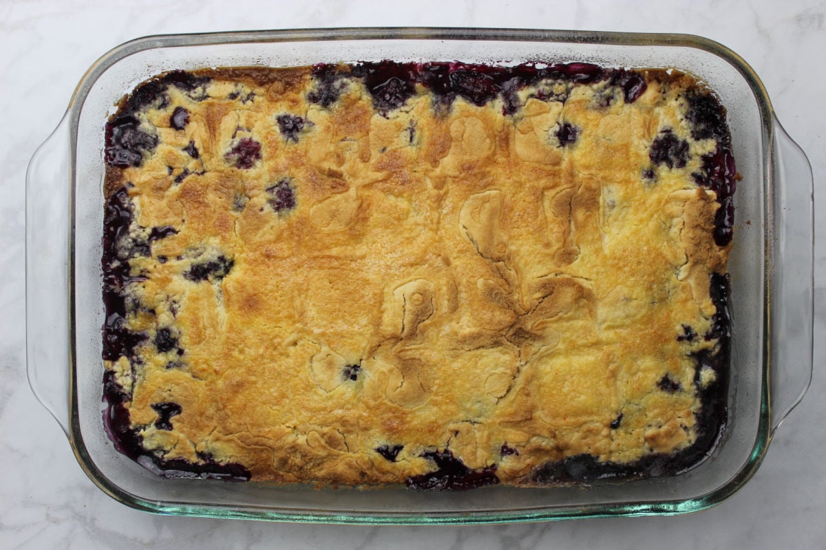 Baked blackberry dump cake with golden crust and areas where blackberries bubble through.