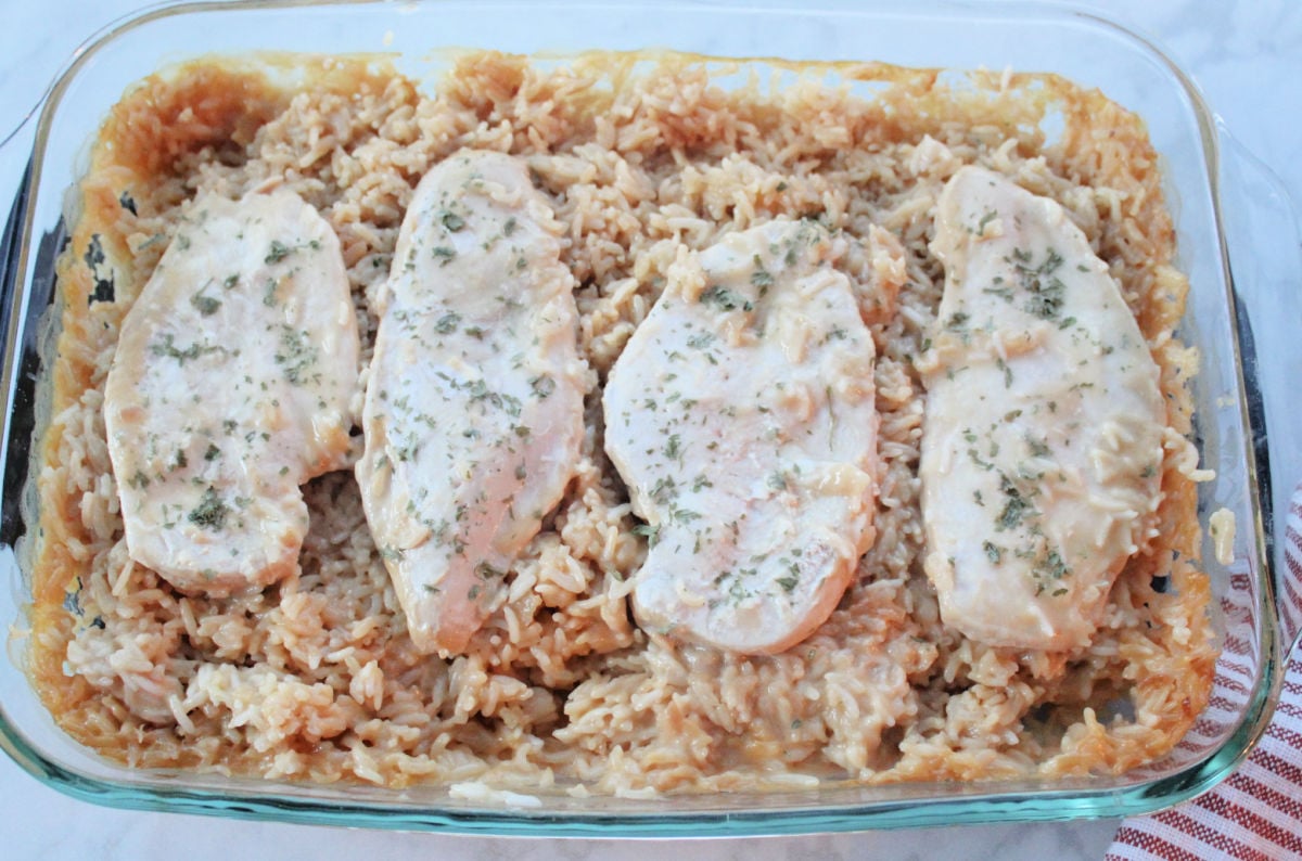 4 pieces of cooked and seasoned chicken pieces on top of cooked and creamy seasoned rice