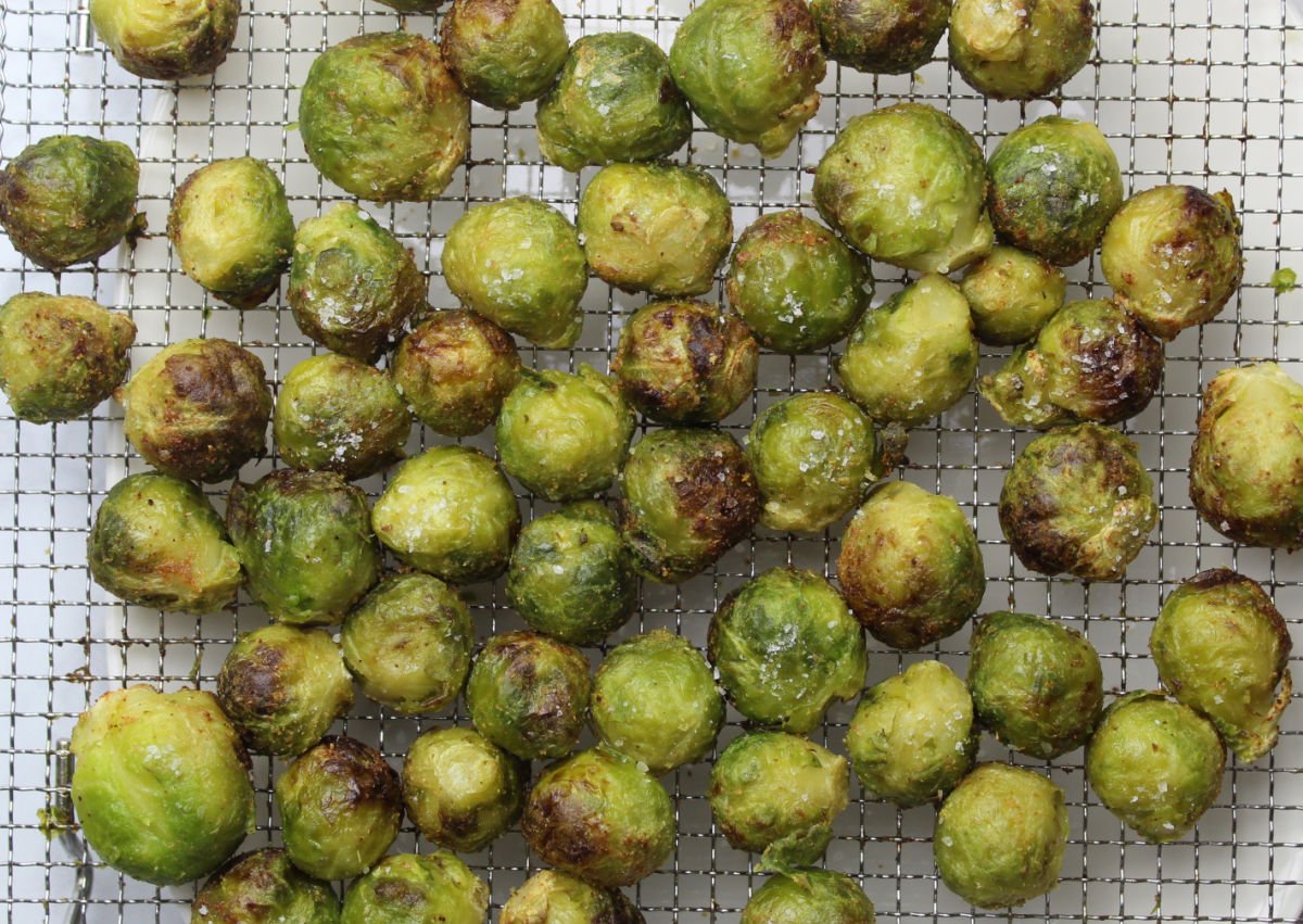 cooked and seasoned brussels sprouts on an air fryer tray.