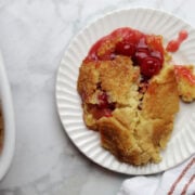 A piece of cherry pineapple dump cake. It looks like a cobbler with a delicious topping with pie cherries peeking through the topping.