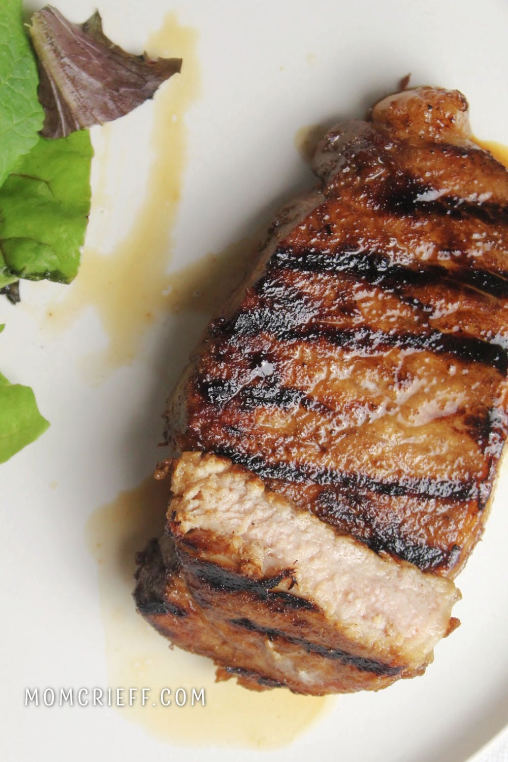 marinaded pork chop with a piece cut through to see how juicy the meat is. 