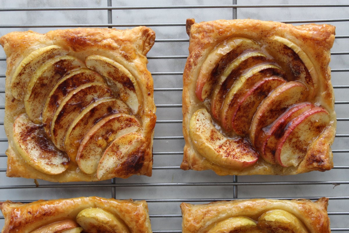 glazed apple tarts sitting on a wire rack to cool.