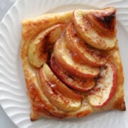 an apple tart made with puff pastry on a white plate.