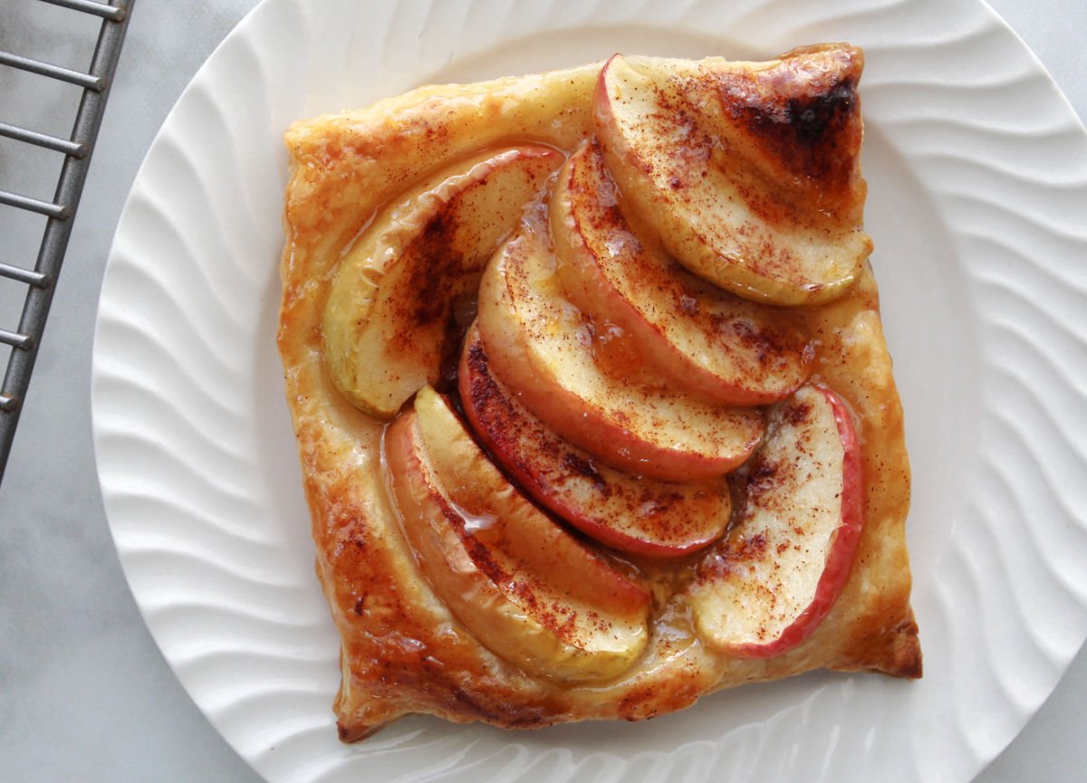 an apple tart made with puff pastry on a white plate.