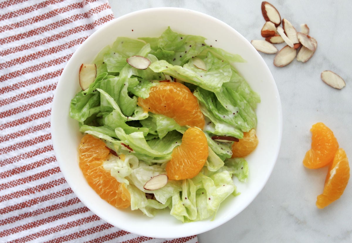 Mandarine orange salad with mandarin slices and almonds for garnish in a white bowl.