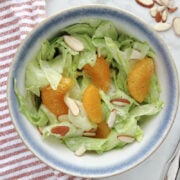 Mandarin orange salad in a bowl. Salad contains lettuce, mandarin oranges, poppyseed dressing and juicy slices of mandarin oranges.