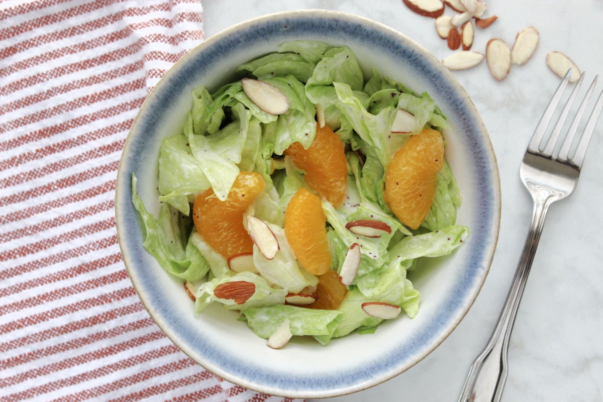 Mandarin orange salad in a bowl.  Salad contains lettuce, mandarin oranges, poppyseed dressing and juicy slices of mandarin oranges.