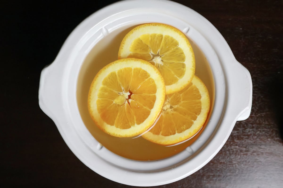 summer simmer pot with orange slices and water is muddied with some vanilla extract.