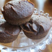 three pumpkin brownie muffins on a clear plate.