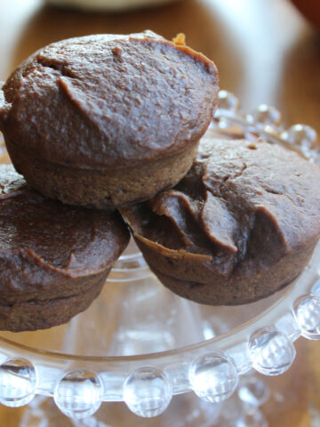 three pumpkin brownie muffins on a clear plate.