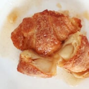 two apple dumplings on a plate with one cut open so you can see the apples in the baked crescent roll.