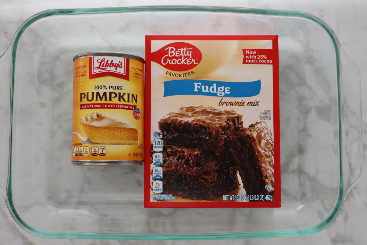 A can of pumpkin puree and a box of brownies in a baking dish.
