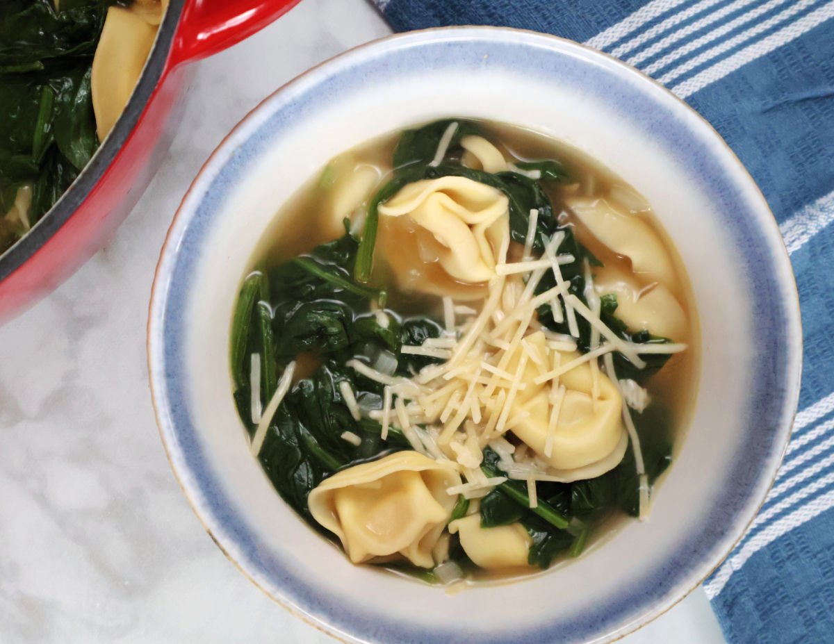 Spinach tortellini soup wsprinkled with parmesan cheese. 