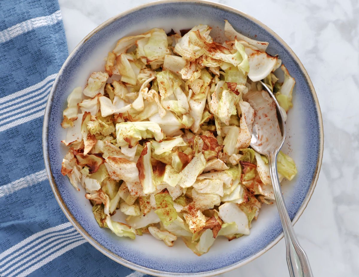 Air fried cabbage, seasoned with paprika for some color, in a white and blue bowl.