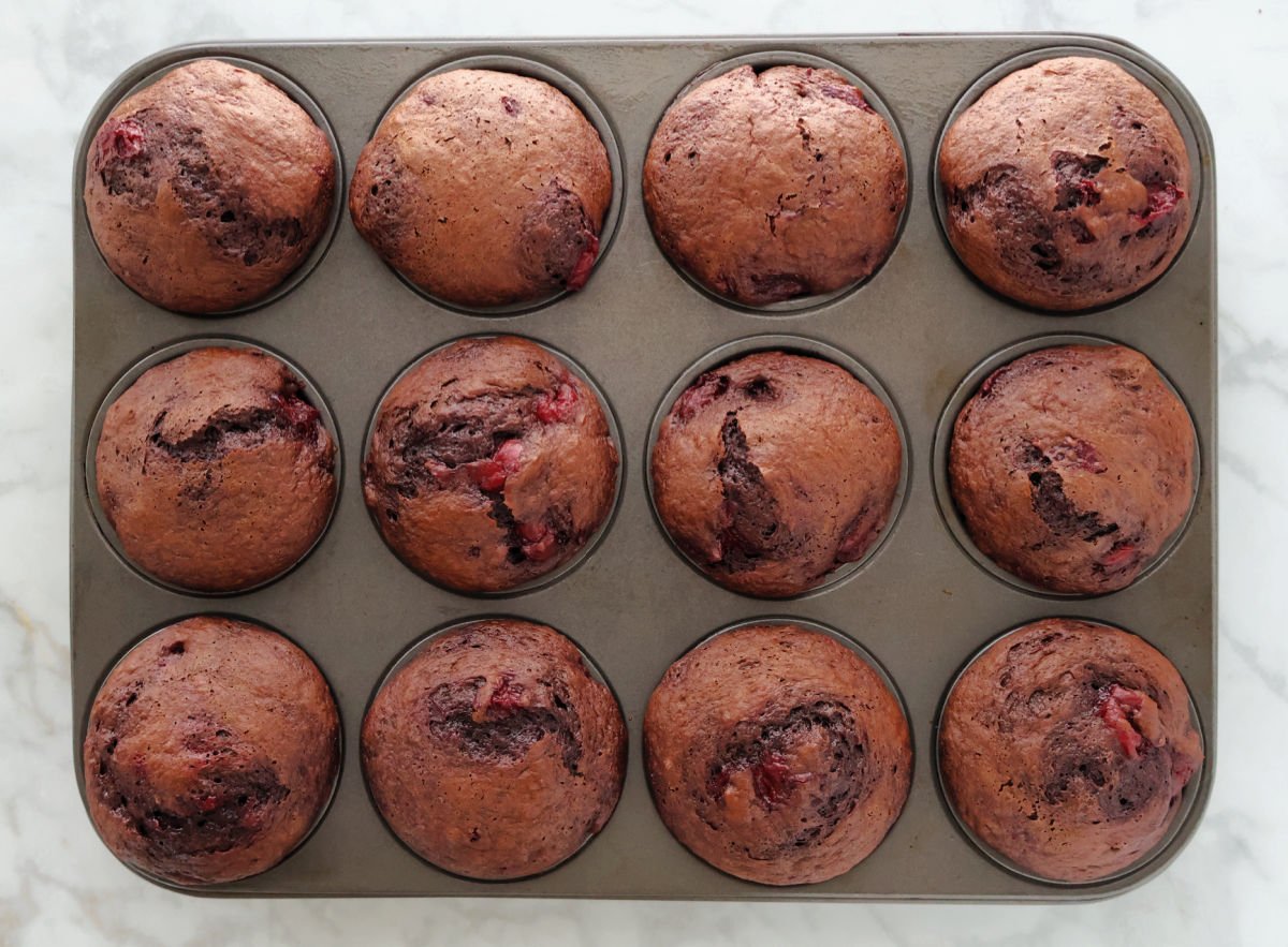 a dozen chocolate cherry muffins fresh out of the oven.
