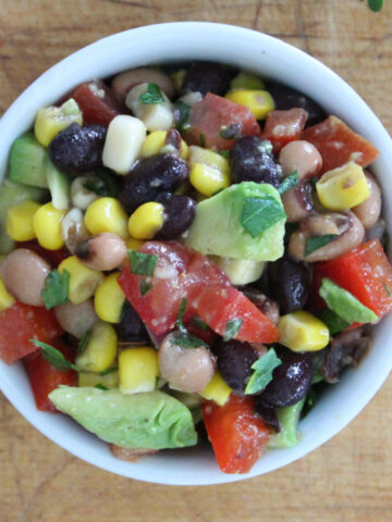 A side dish of fresh cowboy caviar made with black beans, corn, tomatoes, blackeyed peas and a fresh homemade balsamic dressing