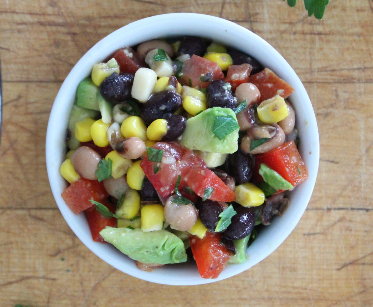 A side dish of fresh cowboy caviar made with black beans, corn, tomatoes, blackeyed peas and a fresh homemade balsamic dressing