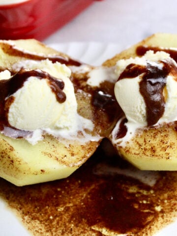 Two halves of apple with a cinnamony sauce with a scoop of ice cream on each apple half.