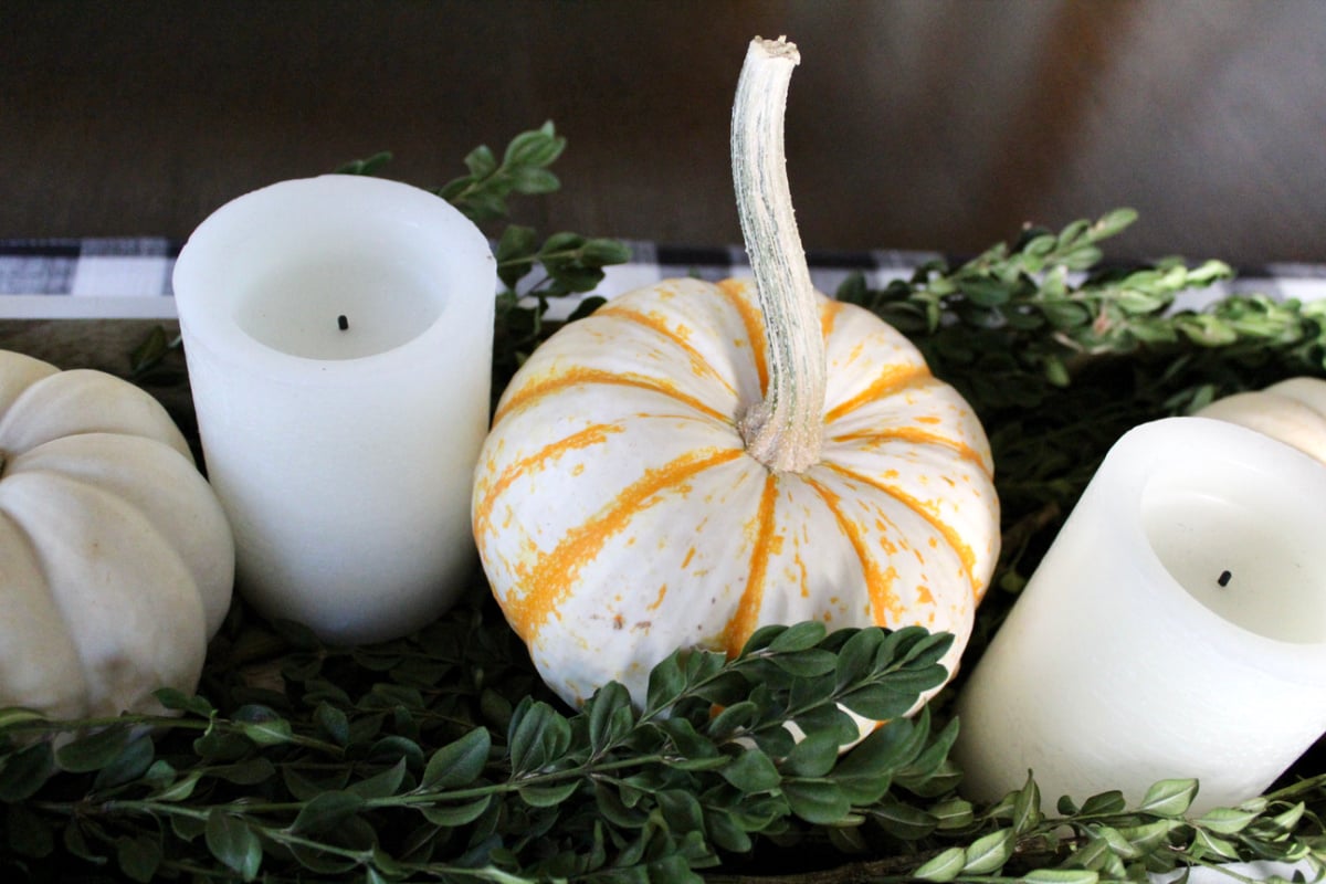 small white pumpkins and white candles on green boxwood clippings