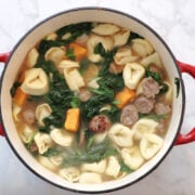 Sausage spinach tortellini soup with sweet potatos in a red dutch oven.