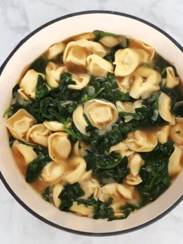 Spinach tortellini soup in a red pot. Resulting soup took 15 minutes