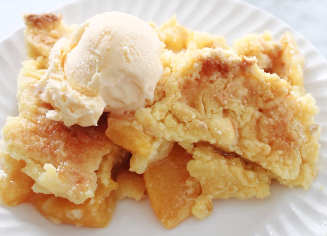 3 ingredient peach cobbler. You can see the bottom layers of peaches covered with a crumbly crust. And the scoop of ice cream makes this dessert look amazing!
