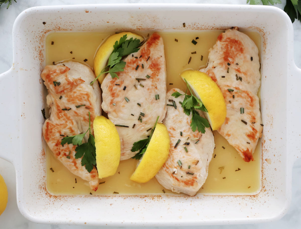 baked rosemary chicken in a butter, lemon and chicken broth. Garnished with lemon wedges, sprinkle of fresh minced rosemary and  sprigs of parsley.