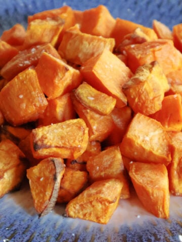 Air fried sweet potato cubes on a blue dish.