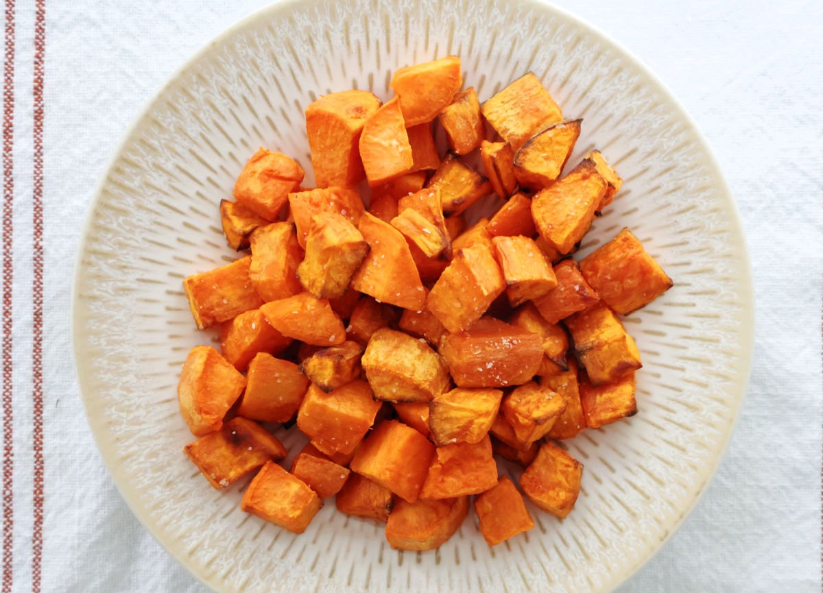 Air fried sweet potato cubes on a cream colored plate.