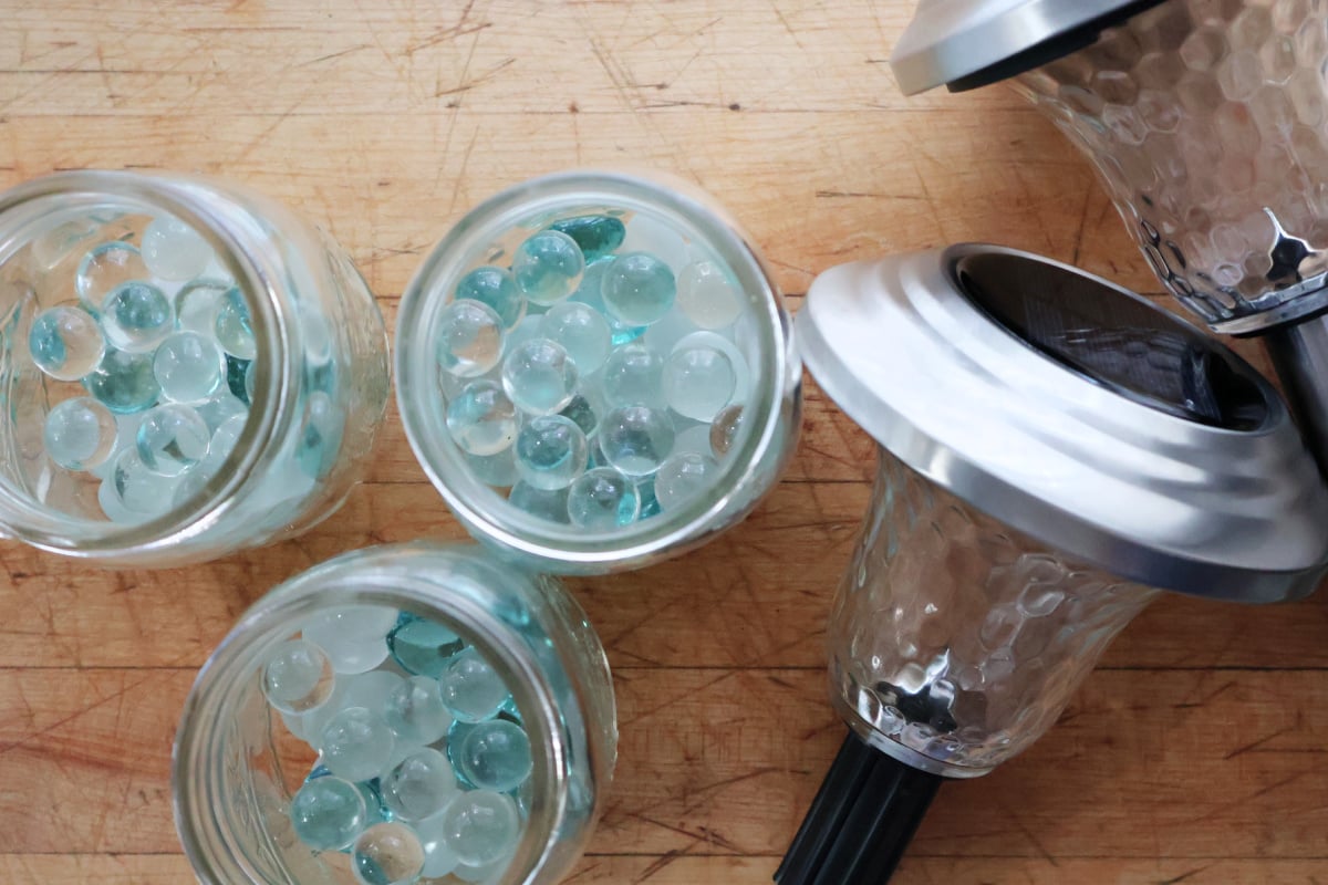 mason jars full of marbles with solar lights laying beside them. 