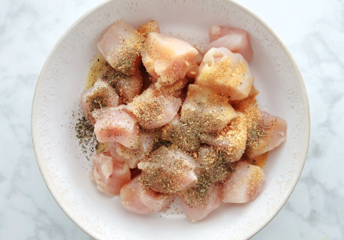 Italian seasonings added to bowl of cut up chicken