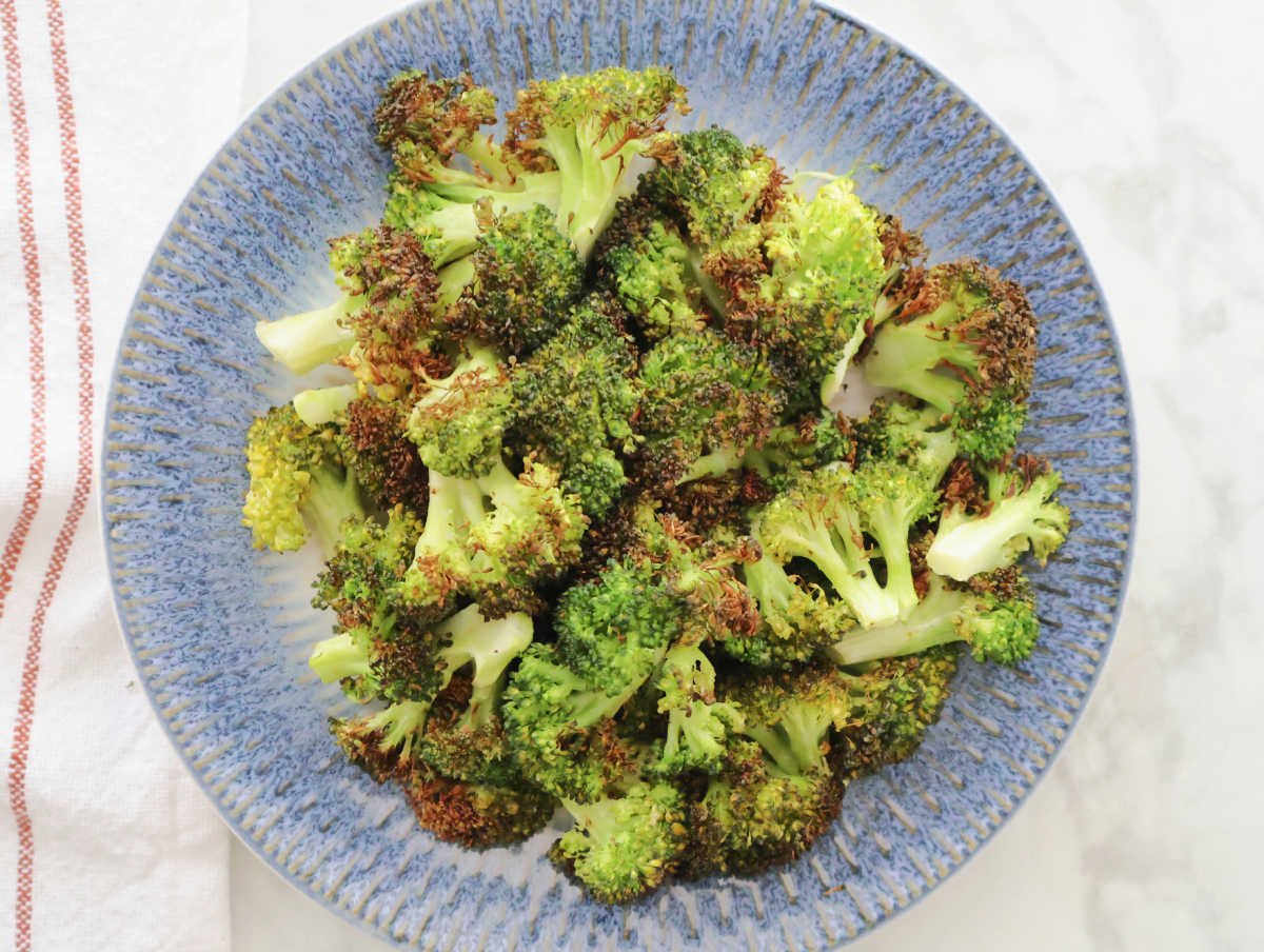 a blue plate with air fried broccoli that is slightly charred.  