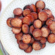 cooked air fryer kielbasa. The kielbasa is cut into coins and served on a white plate.