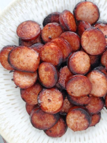 cooked air fryer kielbasa. The kielbasa is cut into coins and served on a white plate.