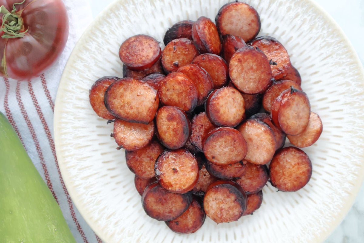 cooked air fryer kielbasa. The kielbasa is cut into coins and served on a white plate.