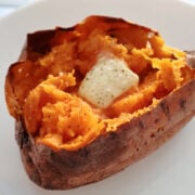 An air fried sweet potato with a pat of butter melting in it and salt and pepper on it.