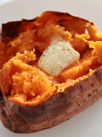 An air fried sweet potato with a pat of butter melting in it and salt and pepper on it.