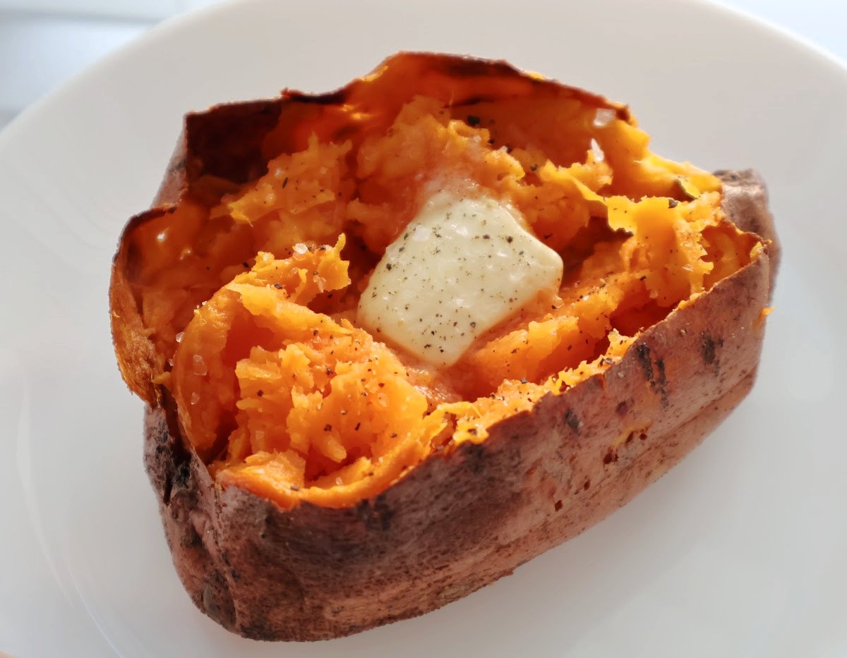 An air fried sweet potato with a pat of butter melting in it and salt and pepper on it. 