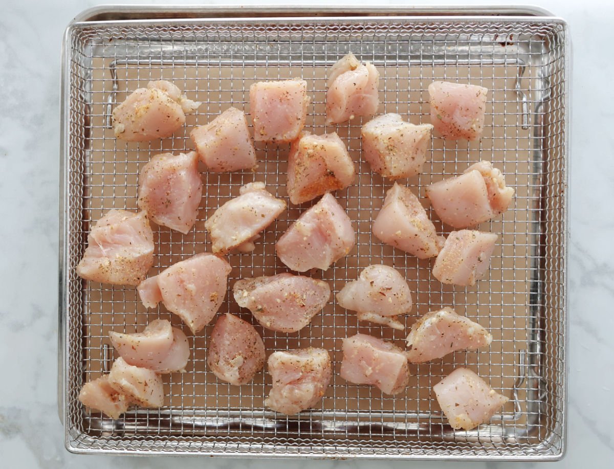 air fryer basket with seasoned cut up chicken ready to be cooked.