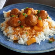 Meatballs on rice with a sweet and sour sauce drizzled on top of the meatballs and rice. Pineapple tidbits are visible in the sauce.