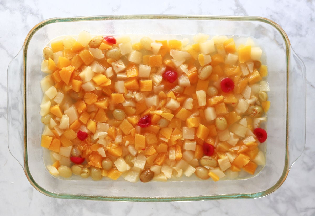 fruit cocktail spread in the bottom of a glass baking dish.