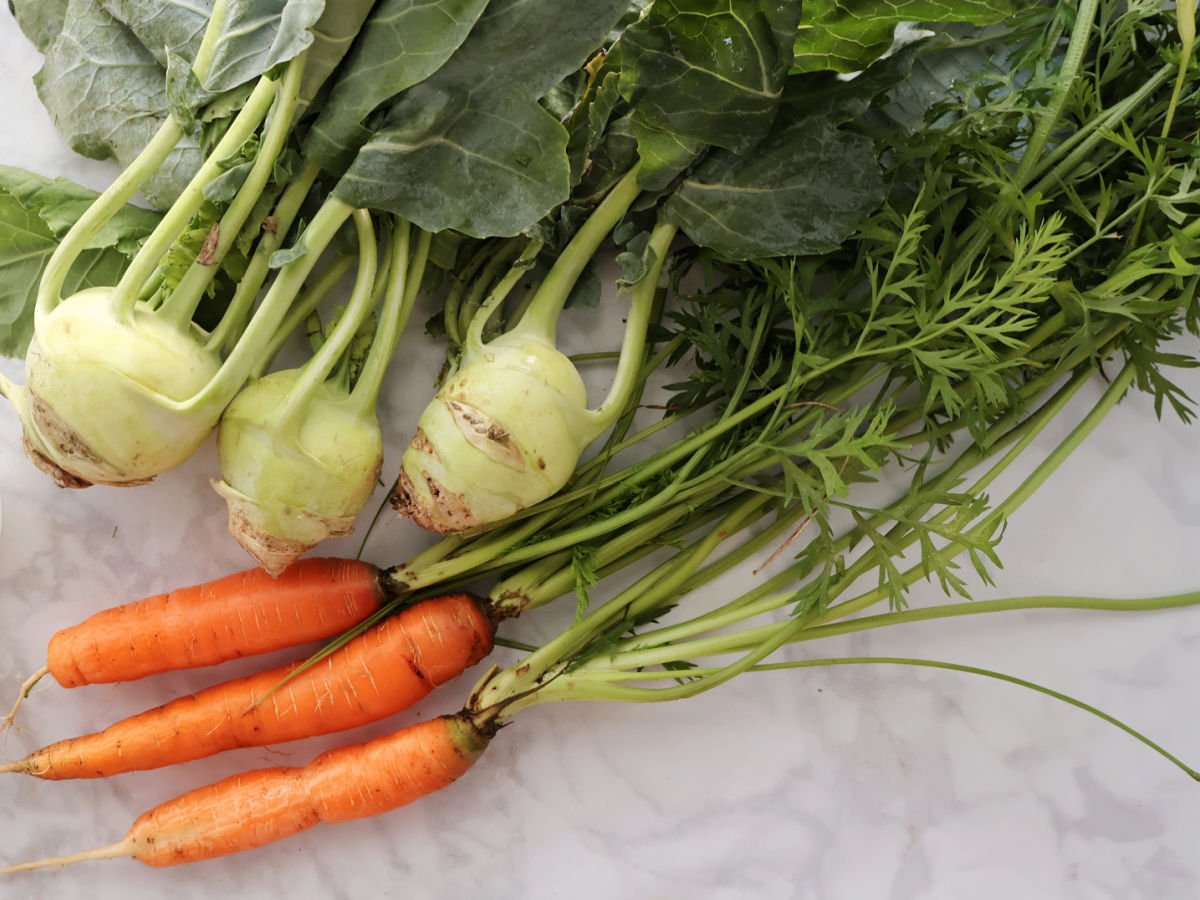 Three Kohlrabi and three carrots with greens still attached.