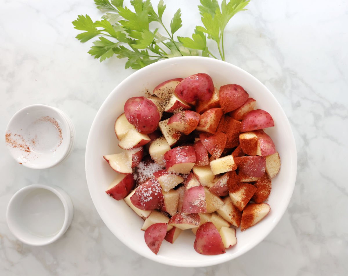 Cut up red potatoes with oil and seasonings sprinkled on top.