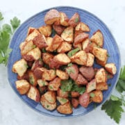 Air fryer roasted red potatoes garnished with parsley swerved on a blue plate.