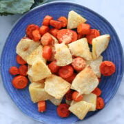 cut up kohlrabi and carrots, roasted in the oven with melted slightly golden parmesan cheese on top. Shown on a blue plate.