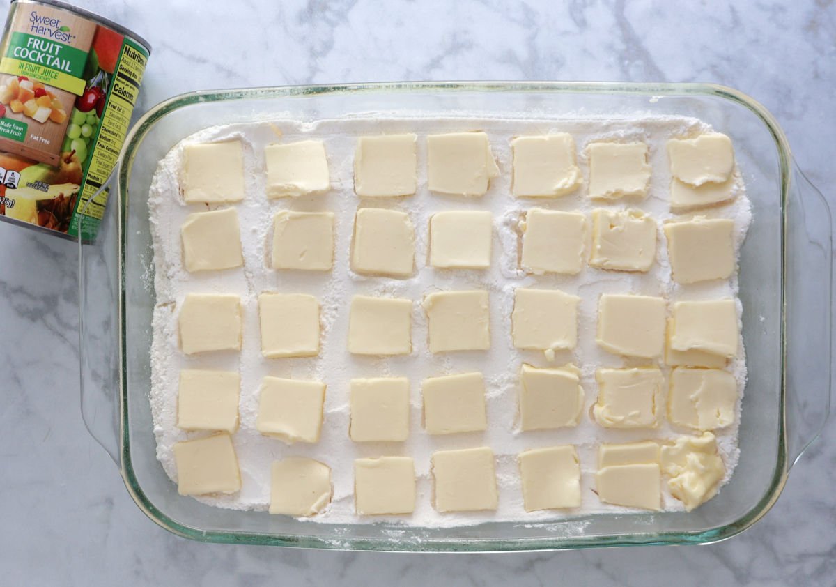 thin slices of butter evenly spread on top of dry cake mix. This fruit cocktail dump cake is complete and ready for the oven. 