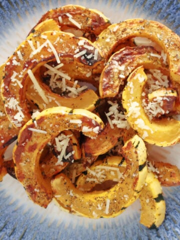 Sliced and air fried delicata squash with italian herb seasoning and parmasan cheese sprinkled on top.