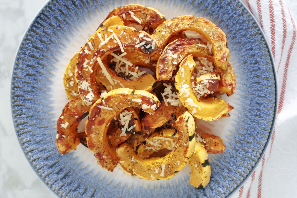 Sliced and air fried delicata squash with italian herb seasoning and parmasan cheese sprinkled on top.