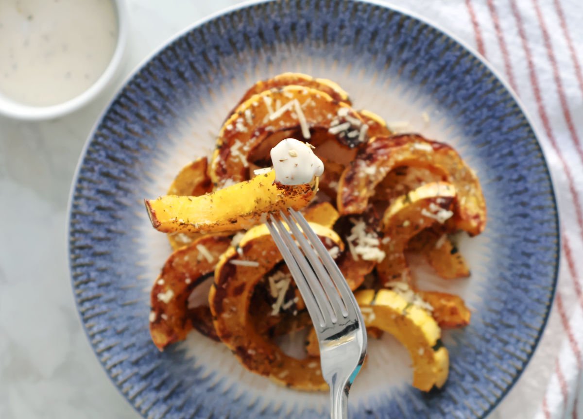 A piece of air fried delicata squash on a spoon with a little ranch dressing on it. 